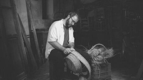 Artesà trenant una cistella d'espart al taller